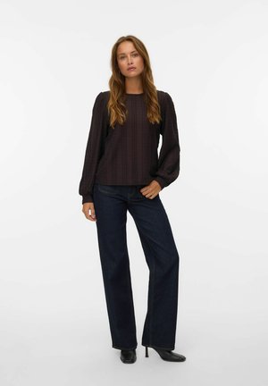 Mørk struktureret langærmet top med rund halsudskæring, parret med højtaljede mørkeblå brede jeans og sorte hælede støvler.