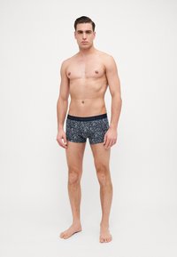 Boxer shorts bleu marine avec un motif moucheté, ceinture élastique portant le logo "Emporio Armani" et un design ajusté.