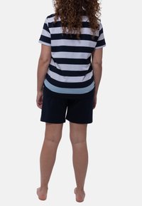 Lyhytnukkainen raitapaita, jossa on tummansinisiä ja valkoisia raitoja, yhdistettynä tummansinisiin shortseihin. Kangas näyttää pehmeältä ja siinä on rento istuvuus.