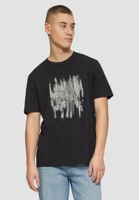 Zwarte katoenen T-shirt met korte mouwen, met een textuurachtig, abstract wit ontwerp van tekst in het midden. Casual pasvorm met een ronde hals.