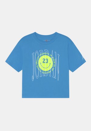 T-shirt bleu à manches courtes Jordan avec un grand texte blanc "JORDAN" et un visage souriant jaune avec le numéro 23 au centre sur le devant.