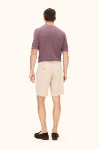 Herrskjorta med kort ärm, ribbad, lila pikétröja tillsammans med beige shorts. Bruna loafers fulländar outfiten. Sedd bakifrån.