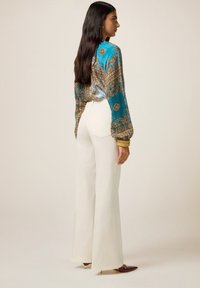 Turquoise gebloemde blouse met brede mouwen, gecombineerd met witte high-waisted broeken. Kenmerkt zich door een soepele textuur en een getailleerde pasvorm, die een moderne silhouette benadrukt.