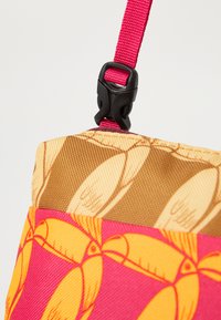 Geantă multicolorată cu o curea roz și un cataramă din plastic negru. Materialul are un model maro și portocaliu pe o parte și un roz vibrant pe cealaltă.