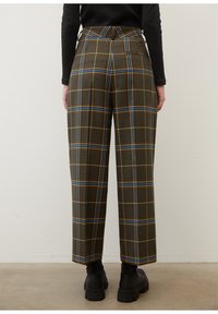 Bruna rutig högmidjade byxor med gula och blå linjer, med skräddarsydd passform och sidfickor, kombinerat med svarta skor.