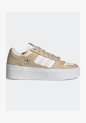 Zapatilla Adidas beige y blanca con suela blanca gruesa, cordones beige, rayas blancas a los lados y logo dorado de Adidas cerca del tacón.