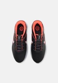 Μαύρα αθλητικά παπούτσια με υφή και νεόν πορτοκαλί λεπτομέρειες, κορδόνια και λογότυπο. Διαθέτουν μαλακή εσωτερική επένδυση και λευκές καουτσούκ σόλες.