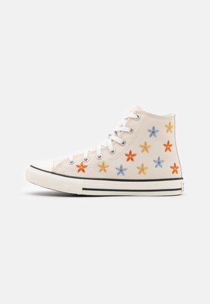 Beige high-top canvas sneaker with white laces and multicolored embroidered blue, orange, and yellow flowers on the side.