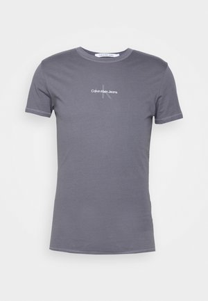 Camiseta de algodón gris con mangas cortas, cuello redondo y un logo minimalista de "Calvin Klein Jeans" impreso en el frontal.