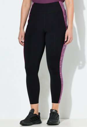 Sorte atletiske leggings med høj talje, udstyret med lyserøde blomsterpaneler i siden og teksturerede detaljer. Båret med sorte atletiske sko.