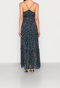 Maxi dress in dark navy with floral pattern, featuring a tiered design, spaghetti straps, and a lightweight, flowing fabric.