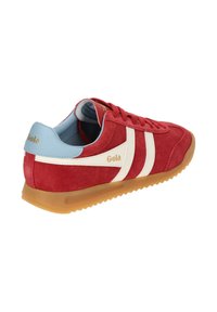 Zapatilla de gamuza roja con franjas blancas y un talón de cuero azul. Presenta una suela de goma. Logo exhibido en el talón.