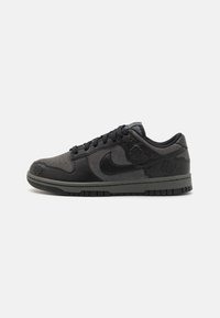 Zapatillas de caña baja en negro y gris oscuro con cordones negros, patrones de rosas en relieve en los paneles de cuero y un swoosh de Nike texturizado en el costado.