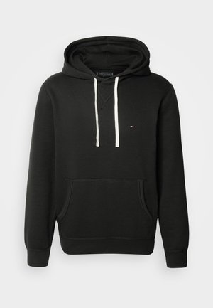 Sudadera negra con bolsillo frontal, capucha con cordón de color claro y pequeño detalle de logo en el pecho. Tejido suave y puños acanalados.