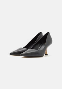 Scarpe con tacco alto in pelle nera con design a punta, tacco a stiletto sottile e superficie liscia. Stile minimalista senza hardware visibile.