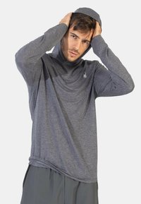 Grå, langærmet hættejakke lavet af tekstureret stof med en snøret hætte og et subtilt logo på brystet. Casual fit, blød og let.