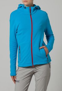 Blauwe fleecejas met een capuchon, voorzien van rode ritsen en twee zijzakken. Glad oppervlak en een strakke pasvorm, ideaal voor buitenactiviteiten.
