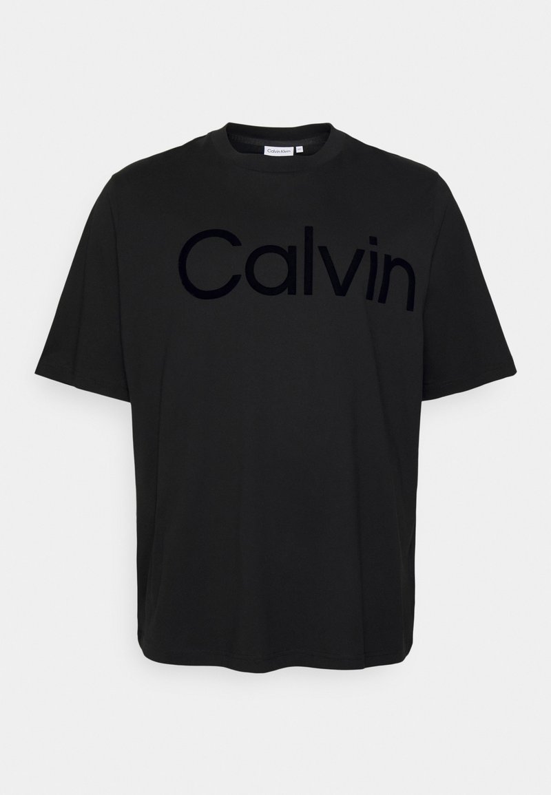 Camiseta de algodón negra con un gran logo en relieve tonal "Calvin" en el pecho. Cuello redondo y mangas cortas, textura suave.