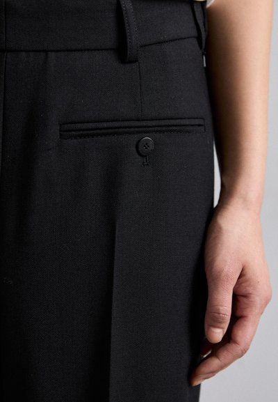 Black dress pants with a flat front, featuring a side pocket, a black button closure, and a smooth, textured fabric.