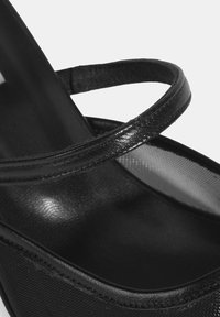 Schwarze High-Heel-Sandale mit zwei strukturierten Riemen. Das Material wirkt glatt mit einem leichten Glanz, verfügt über ein elegantes Design und eine offene Zehenpartie.