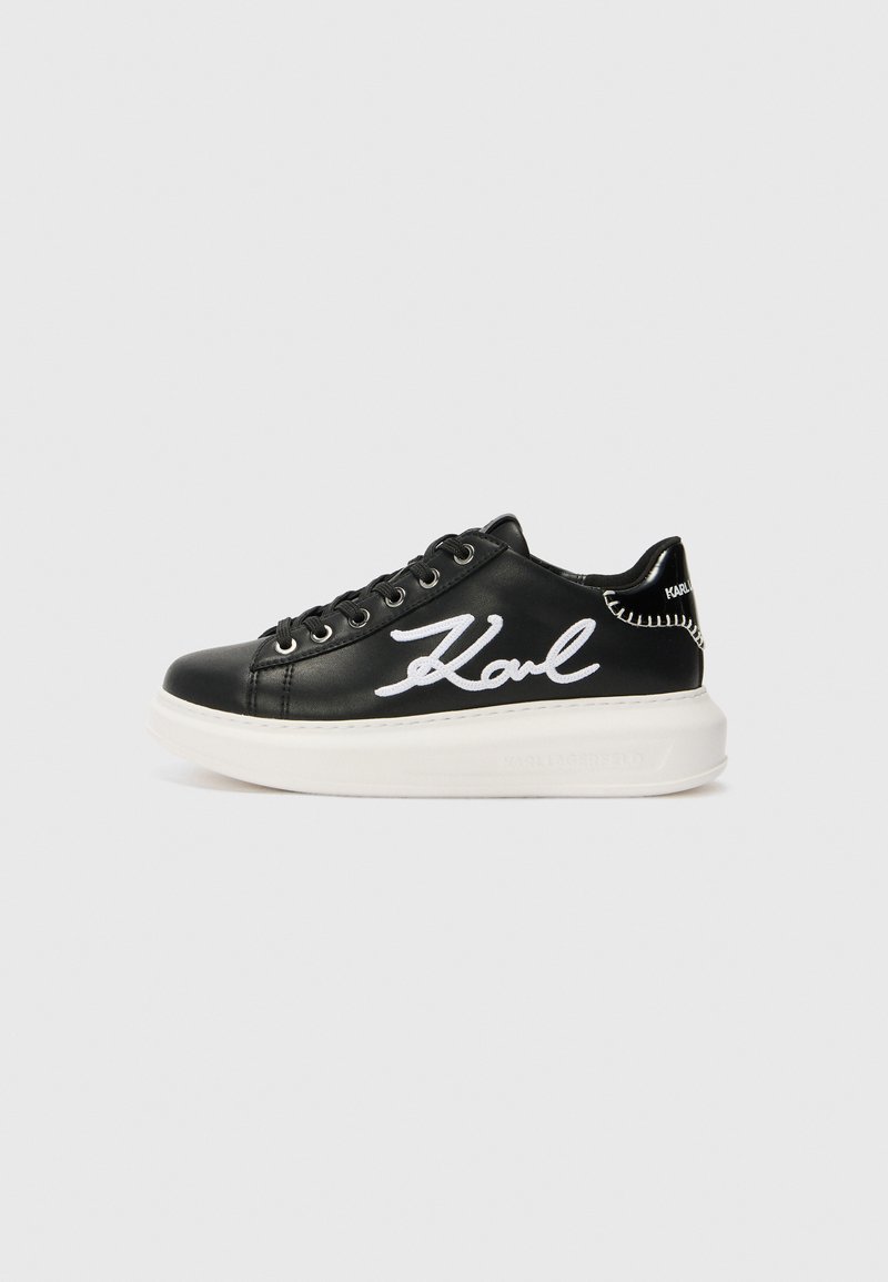 Black leather sneaker featuring white embroidered "Karl" detail, round toe, lace-up design, and a thick white sole with textured accents.