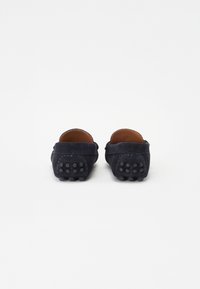 Tumesinised sametist loafers, millel on sile tekstuur, ümar tagaosa, pruuni nahast vooder ja täppidega kummitald.