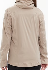 Veste imperméable beige avec un design ajusté, capuche réglable et poignets élastiques.Texture lisse, coutures minimales et ourlet légèrement courbé.