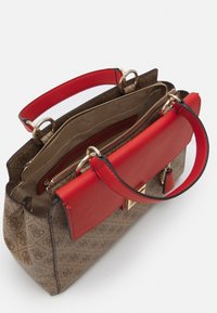 Brązowa torebka w wzory, z czerwoną skórzaną klapą i uchwytami. Wyposażona w złote akcesoria oraz zasuwaną wewnętrzną przegródkę na przechowywanie.