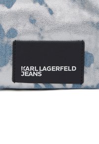 Denim z jasnoniebieskim i białym wzorem tie-dye, z czarną skórzaną naszywką opisaną białym tekstem "KARL LAGERFELD JEANS".