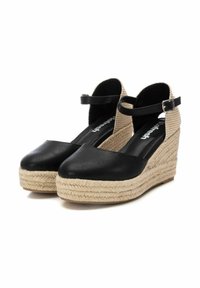 Zapatos de cuña de piel negra con plantilla de yute estilo espadrille y correa ajustable en el tobillo. Superficie lisa, punta redonda, detalles texturizados.