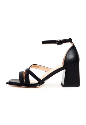 Sandale à talons noirs présentant un bout carré, plusieurs fines bandes, une bride à la cheville avec une boucle et un talon chunky et brillant.