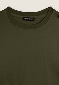 Camiseta verde oliva hecha de una tela suave y lisa. Presenta un cuello redondo acanalado y un pequeño logo en el hombro izquierdo.