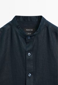 Granatowa lniana koszula z stójką, pięcioma guzikami z niebieskimi guzikami i miękką fakturą. Etykieta mówi "Massimo Dutti".