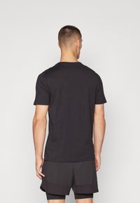 Camiseta de algodón negra con mangas cortas, cuello redondo y corte regular. Textura suave, diseño liso, sin patrones ni acentos visibles.