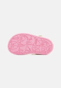 Sole di scarpa beige chiaro in gomma, con una base rosa e un modello dettagliato in stile cartone animato, con il testo "Camper" in rilievo.