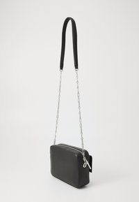 Borsa a tracolla in pelle nera con forma rettangolare, dotata di una tracolla in catena argentata e chiusura con zip. Texture liscia, design minimal.