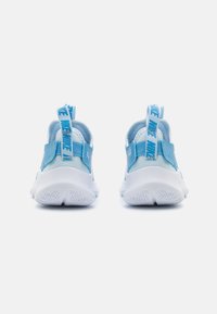 Des chaussures de sport bleues et blanches avec une surface lisse, un talon rembourré, une languette avec du texte et une semelle extérieure blanche texturée.