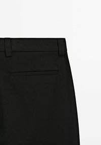 Pantaloni neri con vita piatta, una tasca posteriore singola e un tessuto leggermente texturizzato per un look raffinato.