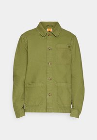 Grön bomulljacka med krage, knappstängning framtill och två stora påsydda fickor. Har en liten logo på bröstfickan.