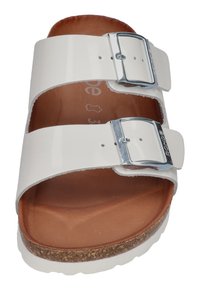 White patent leather sandal with two adjustable silver buckles, brown inner lining, and cork-textured outsole. Flat and open-toed design.