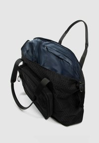 Bolsa tipo duffle negra con un patrón geométrico texturizado, que cuenta con un interior espacioso, forro azul marino y un bolsillo externo con cremallera. Incluye asas dobles.
