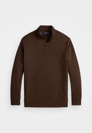 Bruine ritsloze pullover met een hoge kraag, lange mouwen en een subtiele logo-detail op de borst, gemaakt van een zacht materiaal.