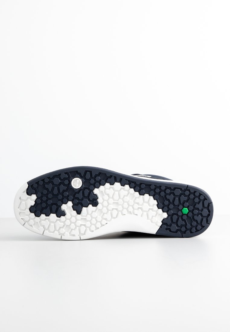 Suola di scarpa con un design testurizzato in bianco e nero caratterizzato da motivi esagonali, bordi lisci e un piccolo accento verde sul tallone.