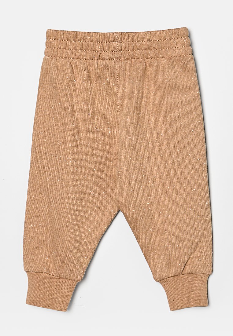 Pantalones deportivos de color tostado con un tejido texturizado, que cuentan con una cinturilla y puños acanalados, y acentos de manchas blancas a lo largo del material.