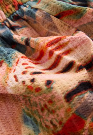 Mehrfarbiger Stoff mit gewebter Textur und abstrakten Blumenmustern. Dominierende Farben sind Pink, Grün und Rot mit weichem Fall.