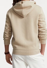 Beige hooded sweatshirt made of soft fabric, features ribbed cuffs and hem, with a simple design and a relaxed fit.