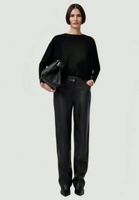 Black oversized sweater, black leather trousers, and a black handbag. The look features a smooth texture and tailored fit.