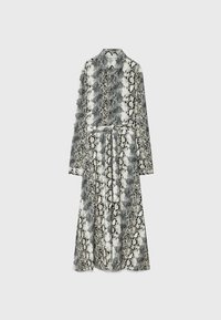 Robe à manches longues boutonnée avec motif peau de serpent noir et blanc et ceinture nouée à la taille sur fond uni.