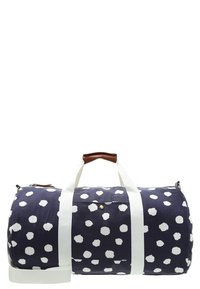 Tummansininen duffel-laukku, jossa on valkoisia pilkkuja, puuvillakangasta, nahkahansikkaat ja valkoinen olkahihna. Sisältää pienen etutaskun.