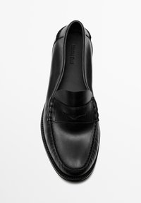 Schwarzer Leder-Slipper mit abgerundetem Zehenbereich, niedrigem Vorderblatt und gewebten Details an der Vorderseite. Glatte Textur mit minimalen Akzenten.